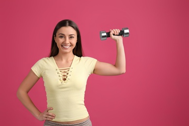 Woman with dumbbell as symbol of girl power on pink background, space for text. 8 March concept