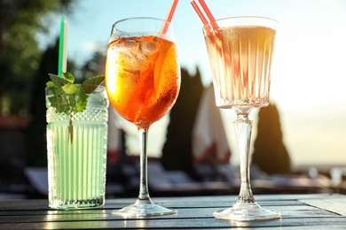 Glasses of fresh summer cocktails on table outdoors at sunset, low angle view