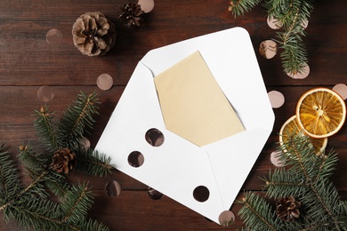 Flat lay composition with blank greeting card and Christmas decor on wooden table, space for text