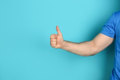 Young man showing thumb sign on color background