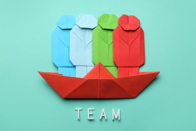 Many colorful paper figures in boat and word Team on light blue background, flat lay. Recruiter searching employee