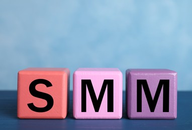 Colorful cubes with abbreviation SMM (Social media marketing) on blue table