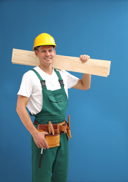 Handsome carpenter with wooden planks on blue background