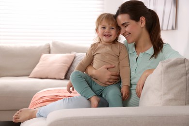 Photo of Mother with her cute little daughter on sofa at home, space for text