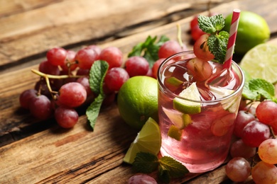 Refreshing drink with soda water, grapes, lime and mint on wooden table. Space for text