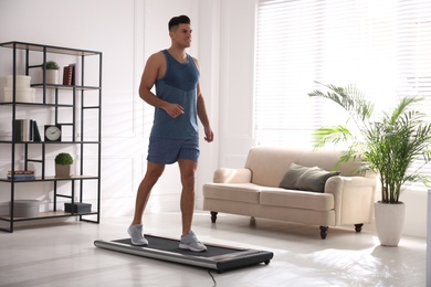 Sporty man training on walking treadmill at home