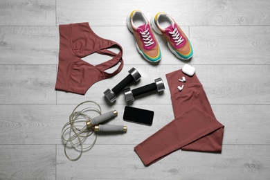 Stylish sportswear and equipment on light wooden background, flat lay