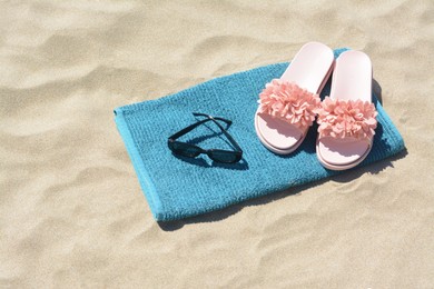 Photo of Towel, flip flops and sunglasses on sand. Beach accessories