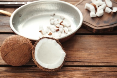 Frying pan with coconut pieces on wooden background