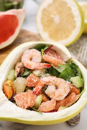 Photo of Delicious pomelo salad with shrimps in half of fruit on table, closeup