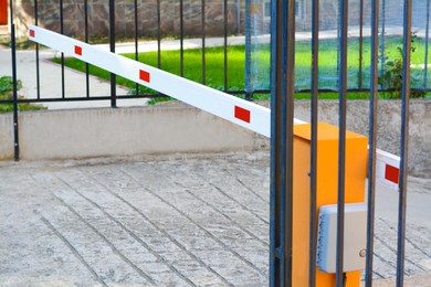 Closed boom barrier near metal fence outdoors