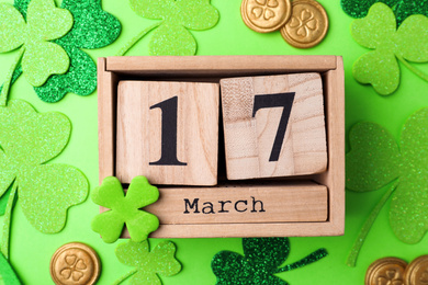 Flat lay composition with wooden block calendar on light green background. St. Patrick's Day celebration