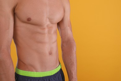 Shirtless man with slim body on yellow background, closeup. Space for text