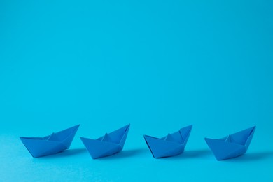 Handmade paper boats on light blue background. Space for text