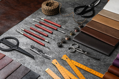 Leather samples and craftsman tools on grey stone background
