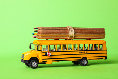 School bus model with color pencils on green background. Transport for students