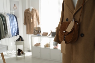Stylish woman's clothes, shoes, accessories in modern boutique, focus on mannequin with coat and bag