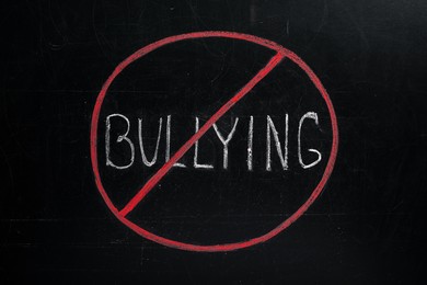 Prohibition sign with word Bullying chalked on blackboard