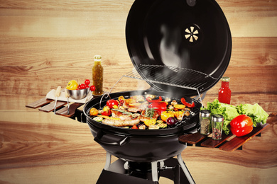 Image of Barbecue grill with meat products and vegetables on wooden background, closeup
