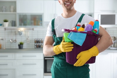 Janitor with bucket of detergents in kitchen, closeup. Cleaning service