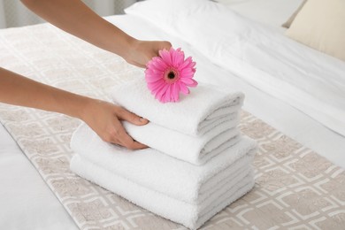 Woman putting flower on fresh towels in room, closeup