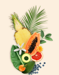 Tropical layout with fresh exotic fruits and green leaves on pale beige background, top view