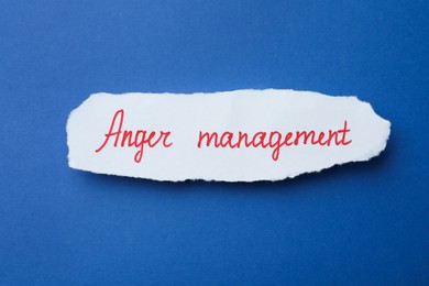 Piece of paper with text Anger Management on blue background, top view