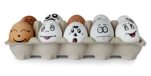 Eggs with different drawn faces in cardboard package on white background