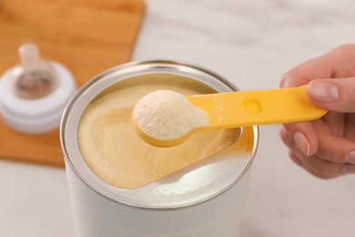 Woman with powdered infant formula at table, closeup. Preparing baby milk