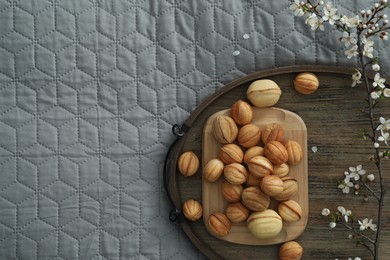 Photo of Delicious walnut shaped cookies with filling and cherry branch on grey blanket, top view and space for text. Homemade popular biscuits from childhood