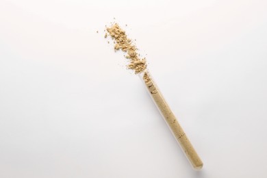 Glass tube with ginger powder on white background, top view