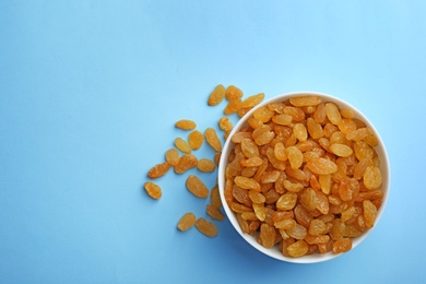 Bowl of raisins on color background, top view with space for text. Dried fruit as healthy snack
