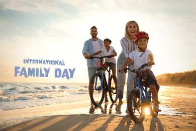 Happy parents teaching children to ride bicycles on sandy beach near sea at sunset. Happy Family Day
