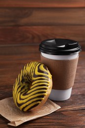 Photo of Tasty frosted donut and hot drink on wooden table