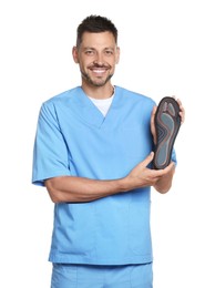Handsome male orthopedist showing insole on white background