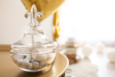 Glass jar with treats on golden table in light room