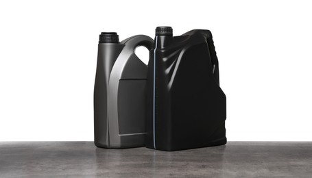 Motor oil in different containers on grey table against white background