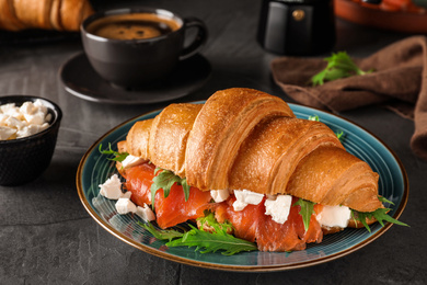 Tasty croissant sandwich with red fish on grey table