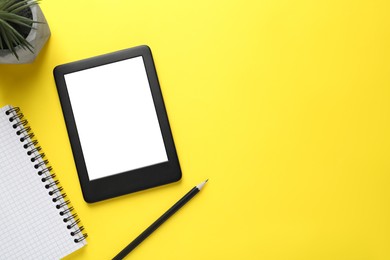 Modern e-book reader, plant, notebook and pencil on yellow background, flat lay. Space for text