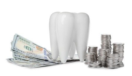 Ceramic model of tooth, dollar banknotes and coins on white background. Expensive treatment