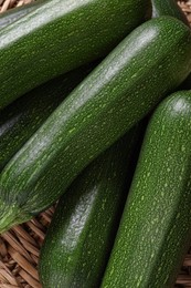 Raw ripe zucchinis on wicker mat, closeup