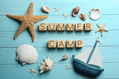 Flat lay composition with phrase SUMMER CAMP made of cubes on light blue wooden background