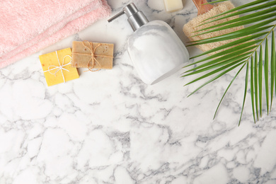 Flat lay composition with soap dispenser on white marble background. Space for text