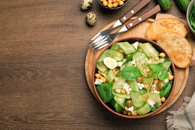 Photo of Delicious cucumber salad and toasted bread served on wooden table, flat lay. Space for text