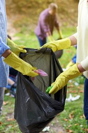 Women with plastic bag collecting garbage in park, closeup
