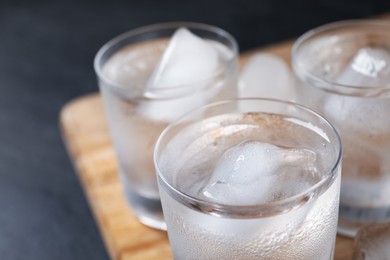 Photo of Shot glasses of vodka with ice cubes on table, closeup