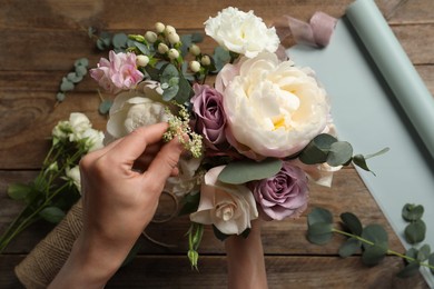 Photo of Florist creating beautiful bouquet at table, top view