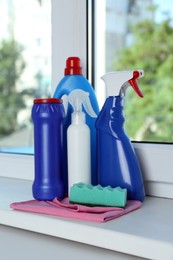 Different cleaning supplies and tools on window sill indoors
