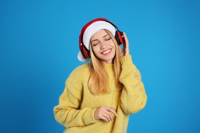 Happy woman with headphones on blue background. Christmas music