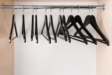 Set of black clothes hangers on wardrobe rail
